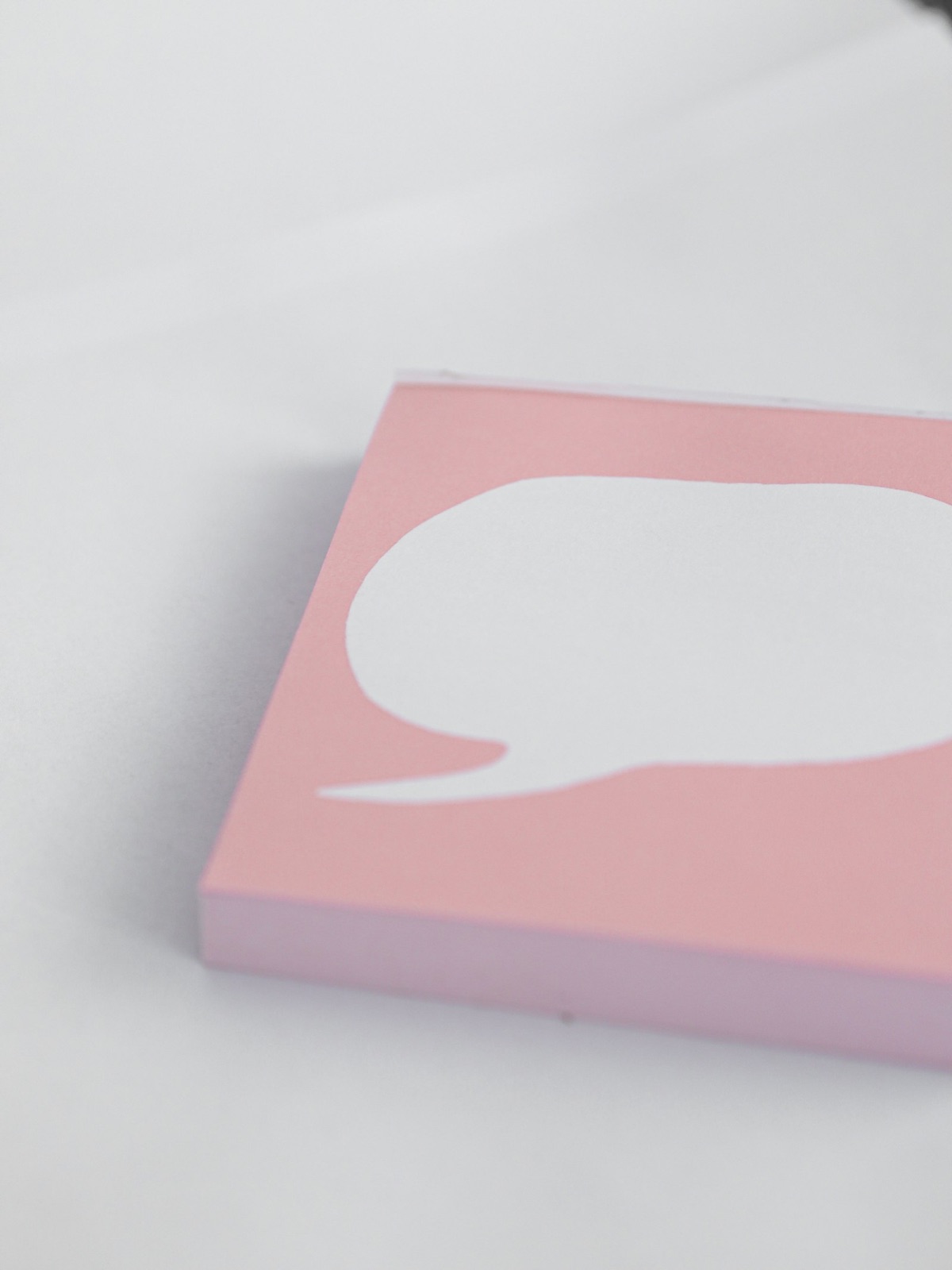 A pink card cut into the shape of a speech bubble, lying on a white surface